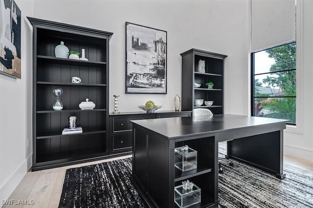 home office with wood-type flooring and built in features