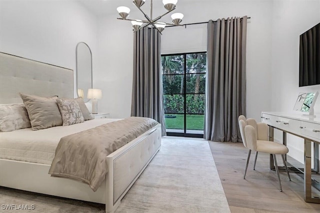 bedroom with a notable chandelier, access to outside, and light wood-type flooring