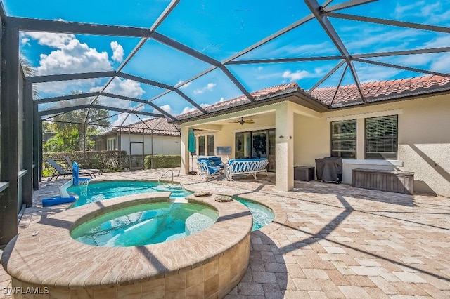 back of property featuring a swimming pool with hot tub, a patio area, glass enclosure, and ceiling fan