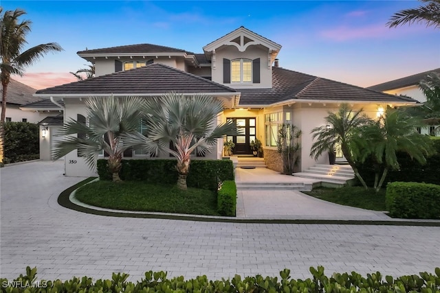 view of front of property with driveway, a tile roof, and stucco siding