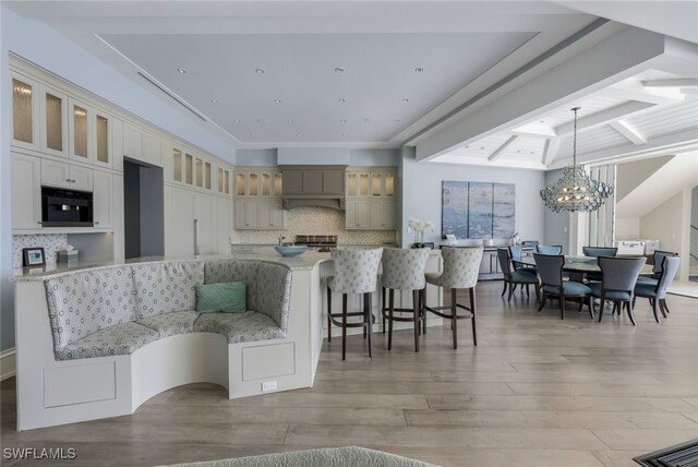 kitchen featuring an inviting chandelier, tasteful backsplash, light stone counters, hanging light fixtures, and light hardwood / wood-style floors