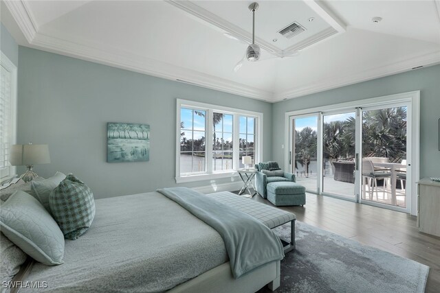 bedroom featuring hardwood / wood-style flooring, access to outside, a raised ceiling, crown molding, and a water view