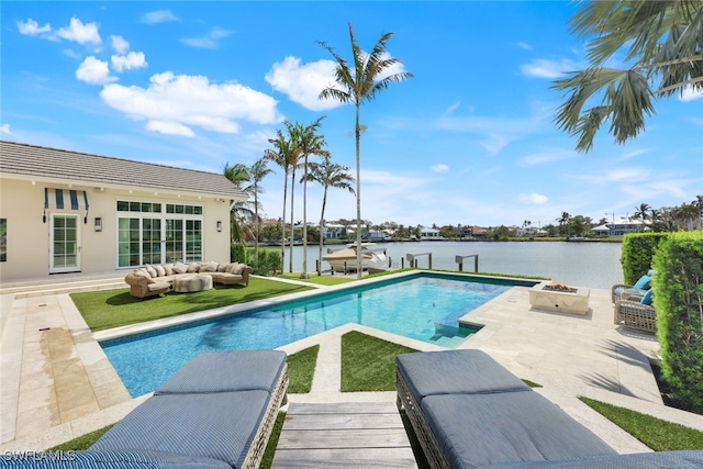 view of swimming pool with a patio area, an outdoor living space with a fire pit, and a water view