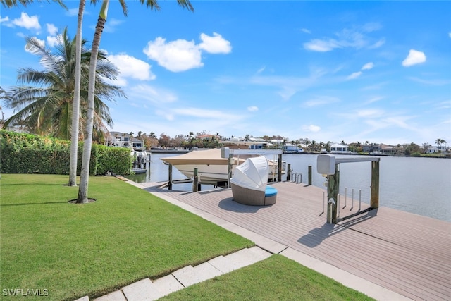 view of dock with a water view, boat lift, and a yard