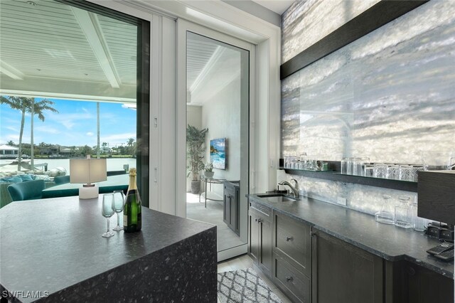 kitchen featuring dark countertops, open floor plan, a sink, and beamed ceiling