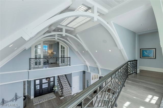 hall featuring high vaulted ceiling, beam ceiling, baseboards, and wood finished floors