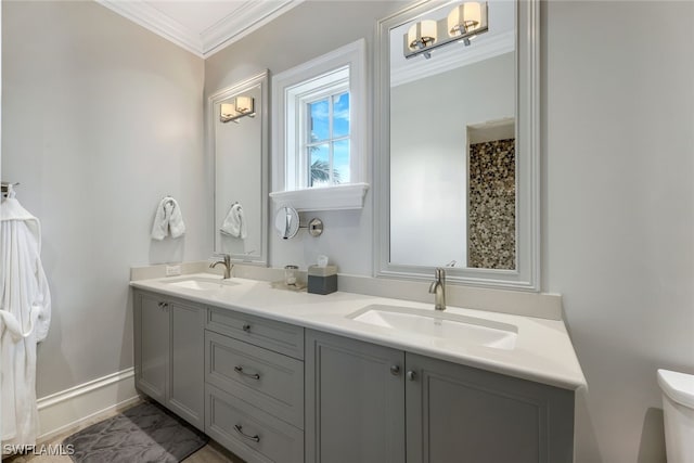 full bath featuring double vanity, a sink, toilet, and crown molding