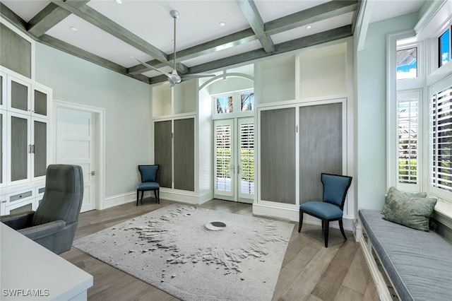 interior space with light hardwood / wood-style flooring, a high ceiling, coffered ceiling, french doors, and beamed ceiling