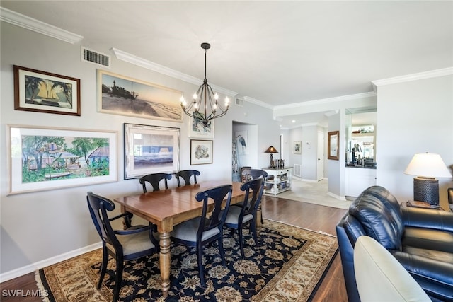 dining room with ornamental molding, hardwood / wood-style flooring, and an inviting chandelier