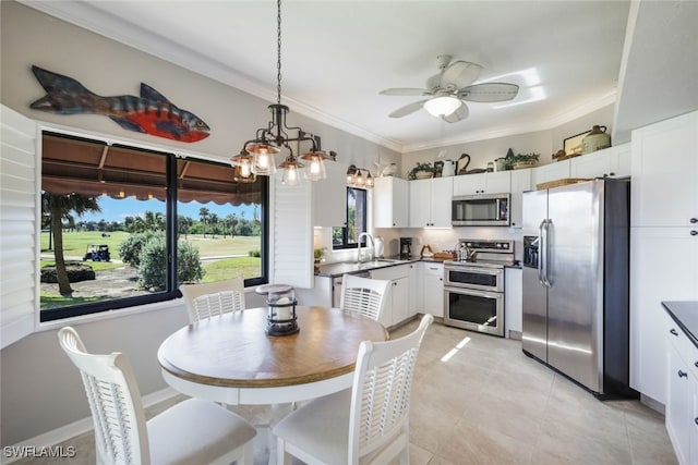 dining space with light tile patterned floors, crown molding, sink, and ceiling fan with notable chandelier