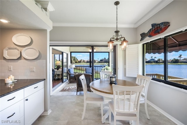 tiled dining room featuring ornamental molding, a chandelier, a water view, and a wealth of natural light