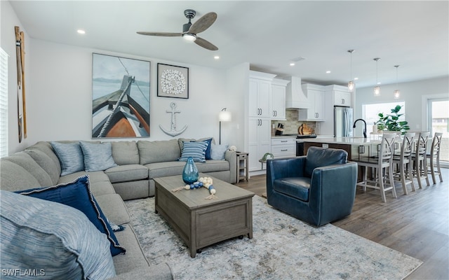 living room featuring sink, light wood-type flooring, and ceiling fan