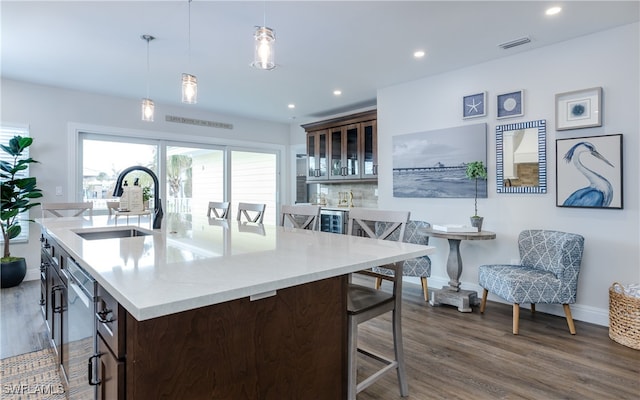 kitchen with a center island with sink, sink, hanging light fixtures, and dark hardwood / wood-style flooring