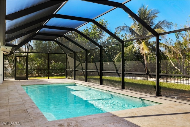 view of swimming pool with glass enclosure and a patio