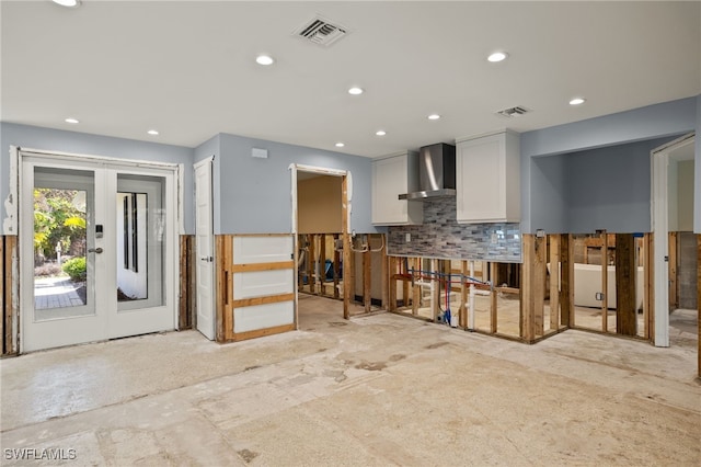 kitchen featuring backsplash, wall chimney exhaust hood, and white cabinets