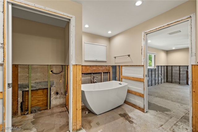 bathroom with a washtub and concrete flooring