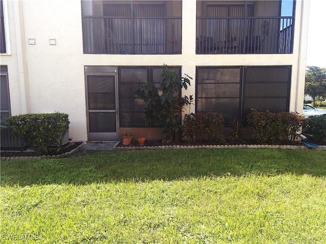 exterior space with stucco siding and a yard