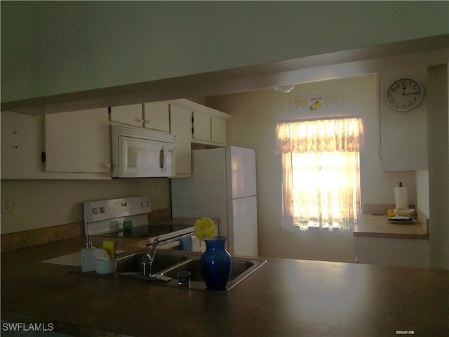 kitchen with white appliances, white cabinetry, and a sink
