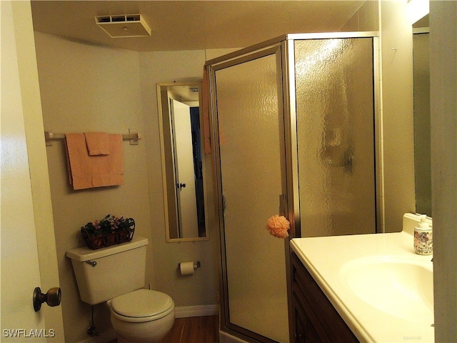 bathroom featuring a shower with door, vanity, and toilet