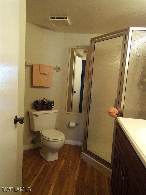 bathroom with vanity, toilet, wood-type flooring, and an enclosed shower