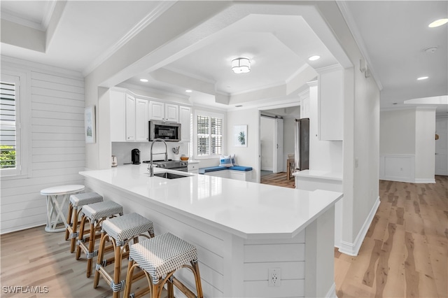 kitchen featuring white cabinetry, stainless steel appliances, kitchen peninsula, a kitchen bar, and a barn door