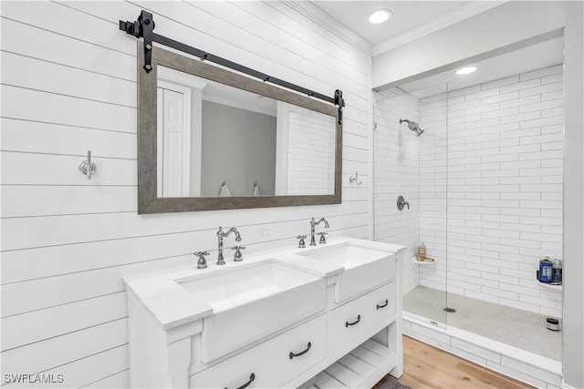 bathroom with a tile shower, vanity, crown molding, wood-type flooring, and wood walls