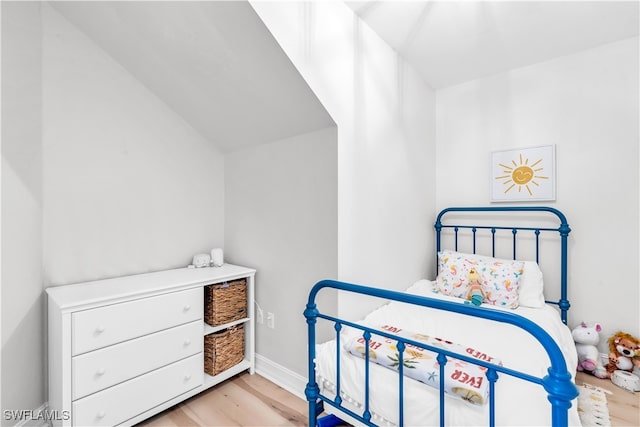 bedroom with vaulted ceiling and light wood-type flooring