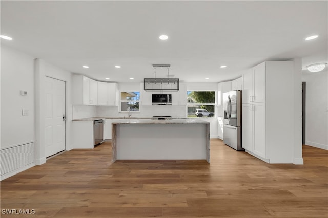 kitchen with a kitchen island, white cabinets, light hardwood / wood-style flooring, and stainless steel appliances