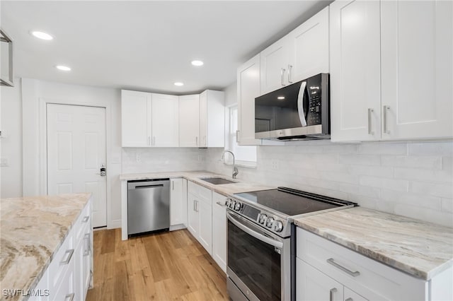 kitchen with light hardwood / wood-style floors, white cabinetry, stainless steel appliances, and sink