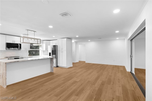 kitchen featuring appliances with stainless steel finishes, white cabinetry, decorative light fixtures, and light hardwood / wood-style floors