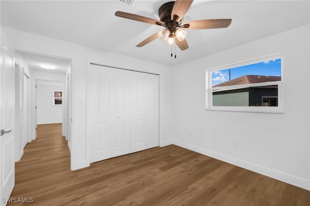 unfurnished bedroom featuring hardwood / wood-style floors, a closet, and ceiling fan