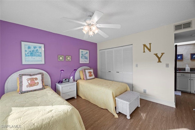 bedroom with dark hardwood / wood-style flooring, a textured ceiling, a closet, and ceiling fan