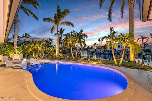 pool at dusk featuring a water view