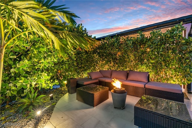 patio terrace at dusk with an outdoor living space with a fire pit