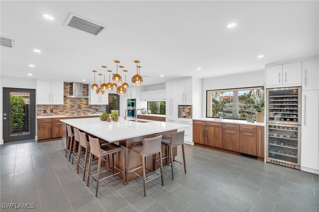 kitchen with a large island, wine cooler, decorative light fixtures, and white cabinets