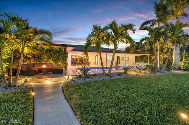 view of front of home featuring a patio area, a pool, outdoor lounge area, and a lawn