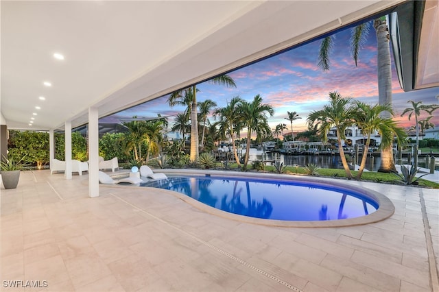 pool at dusk with a water view and a patio area