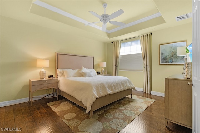 bedroom featuring ornamental molding, ceiling fan, a tray ceiling, and dark hardwood / wood-style flooring