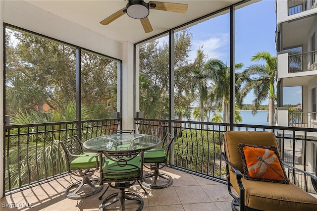 sunroom / solarium featuring a healthy amount of sunlight, a water view, and ceiling fan