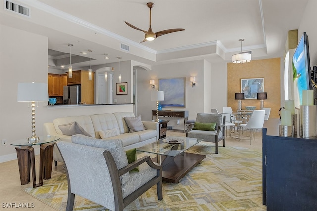 living room featuring crown molding, a tray ceiling, light tile patterned floors, and ceiling fan