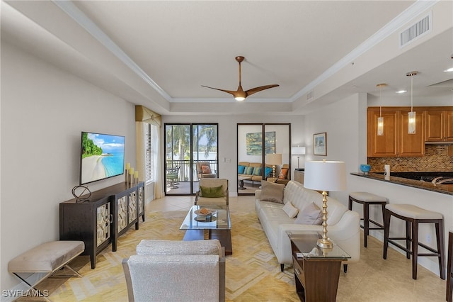 living room featuring crown molding, a tray ceiling, and ceiling fan