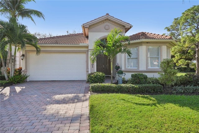 mediterranean / spanish house with a garage and a front lawn