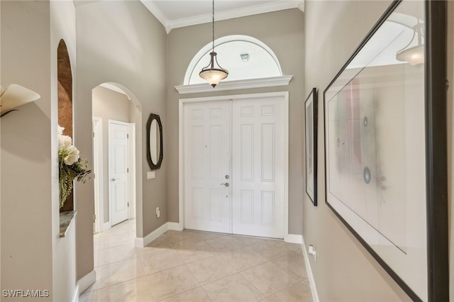 tiled foyer featuring crown molding and a high ceiling