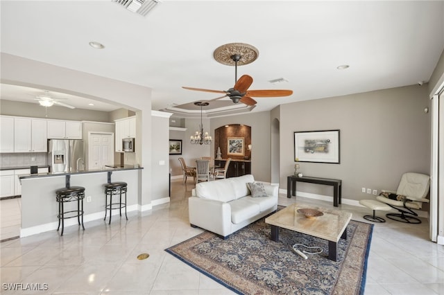 tiled living room featuring ceiling fan with notable chandelier