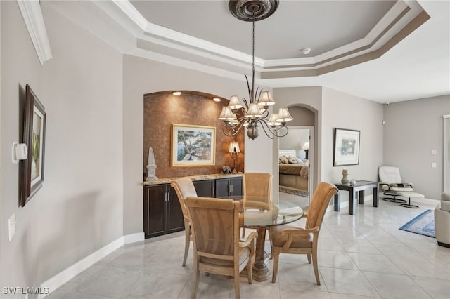 dining space with a tray ceiling, an inviting chandelier, and ornamental molding