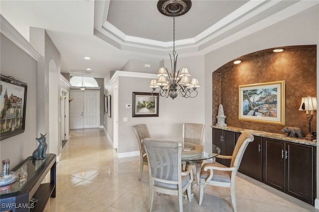 dining area with a raised ceiling, crown molding, and a chandelier