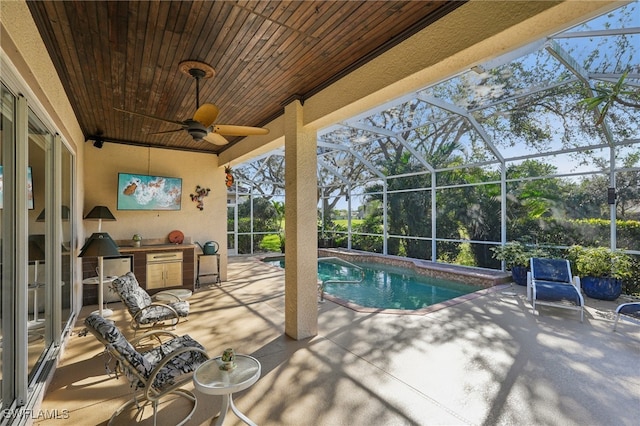 view of swimming pool with a lanai, ceiling fan, a patio area, and exterior kitchen