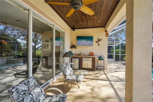 view of patio with ceiling fan, a lanai, and exterior kitchen