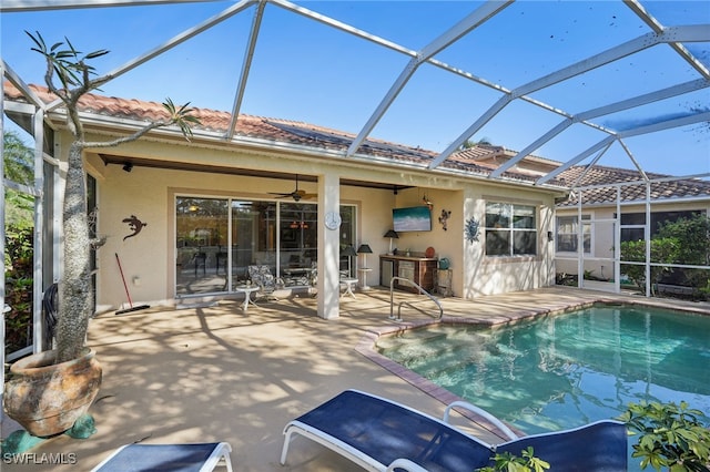 view of pool with a patio area, ceiling fan, and glass enclosure