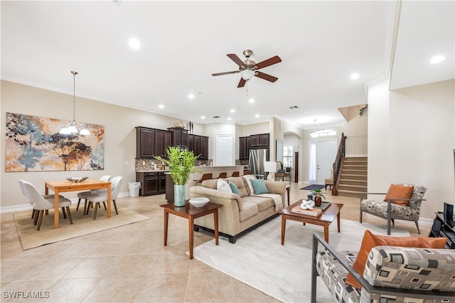 tiled living room with crown molding and ceiling fan with notable chandelier